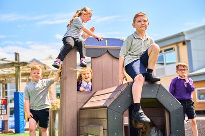 Young children standing on a climbing frame in the school yard 