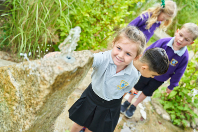 A young girl plays with a water feature at school