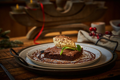 A chocolate brownie with ice cream in a rustic setting. 