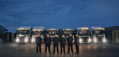 A cinematic portrait of some truck drivers stood in front of their trucks at night. 