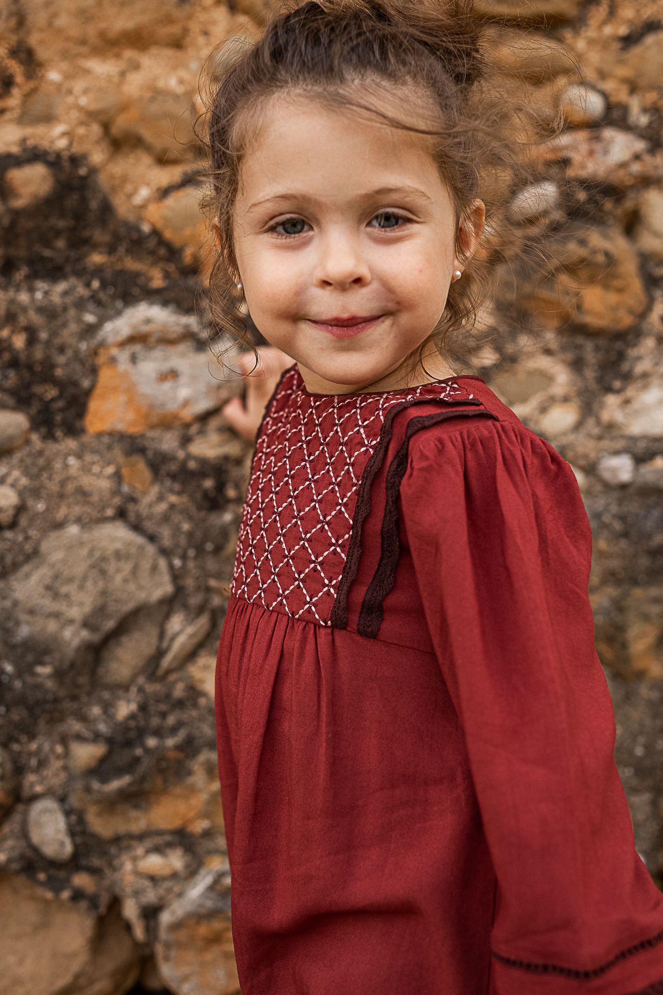 retrato de niña delante de un muro de piedra de una Masia en Pla de l'Estany en cataluña, españa.