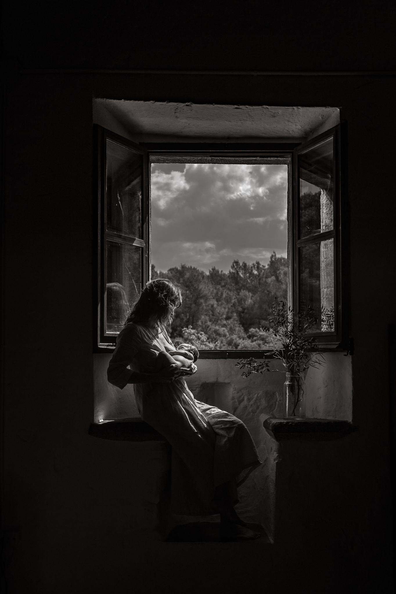madre con dando pecho a su recién nacido iluminada por la luz de su ventana. Manuela Franjou barcelona birth photographer