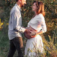 fotografía de una pareja ella está embarazada  de 38 semanas, en los campos floridos de Pla de l'Estany, en girona, españa.