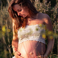 retrato sentada de una mamá embarazada de 38 semanas, en los campos floridos de Pla de l'Estany, en girona, españa.