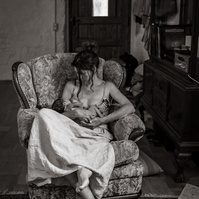 mamá sentada en un sillon, amamantando a su bebe de pocas semanas en plà de l'Estany, girona, spain