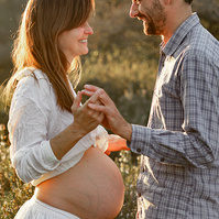 fotografía de una pareja ella está embarazada  de 38 semanas, al atardecer en los campos floridos de Pla de l'Estany, en girona, españa.