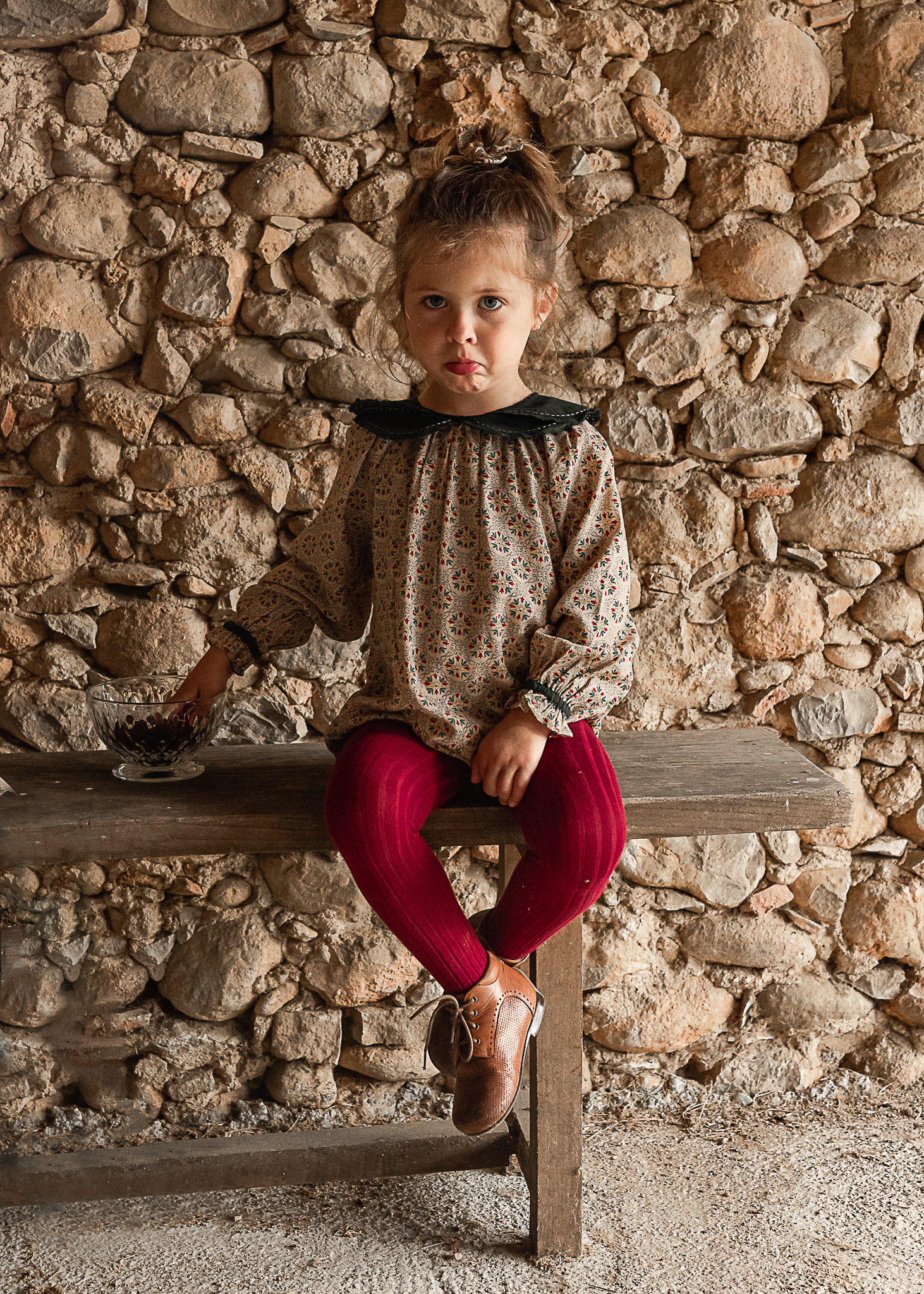 niña sentada en un banco  en un pajar de una Masia en Pla de l'Estany, girona, españa