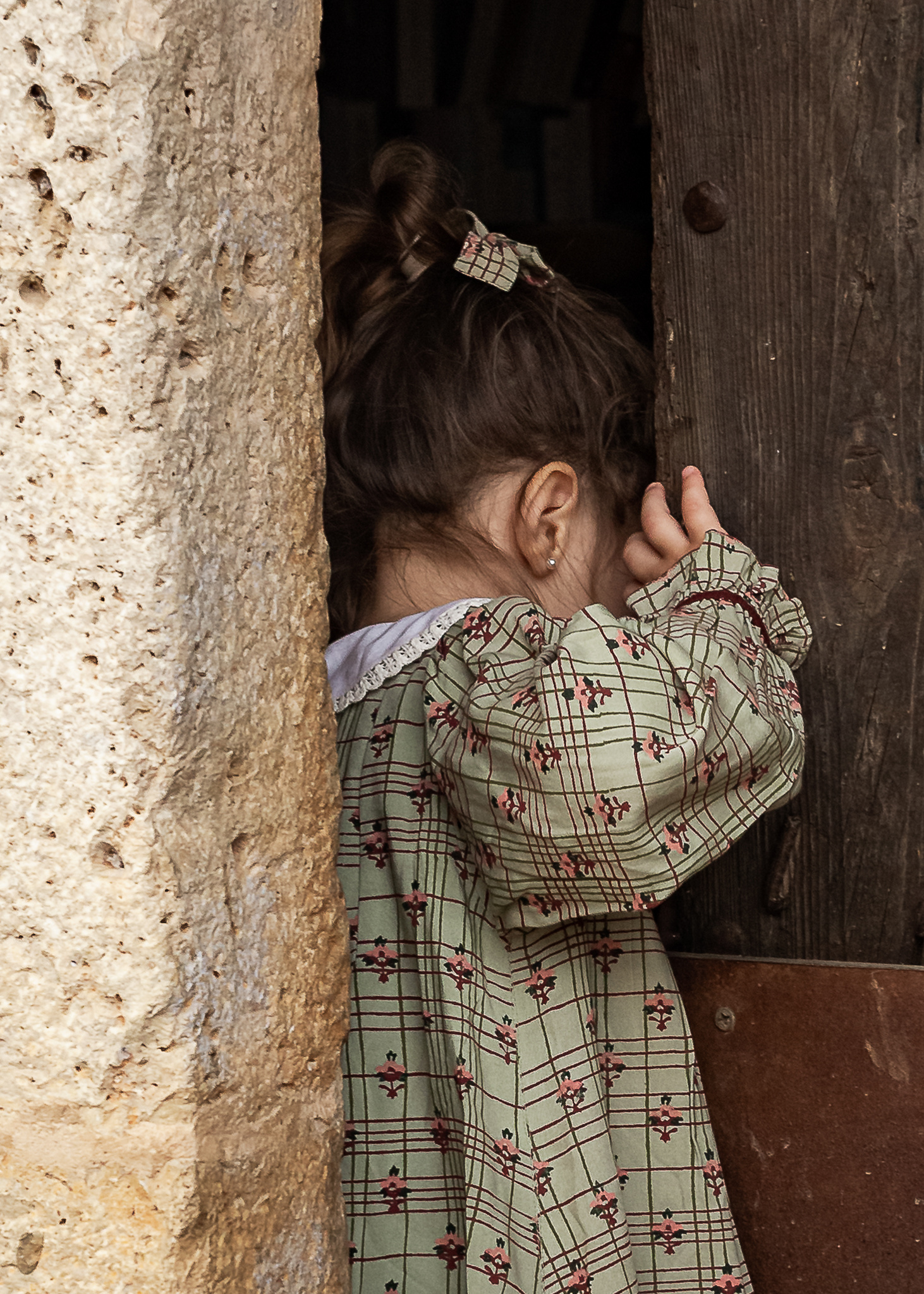 niña mirando por la puerta de una Masia en Pla de l'Estany en cataluña, españa.