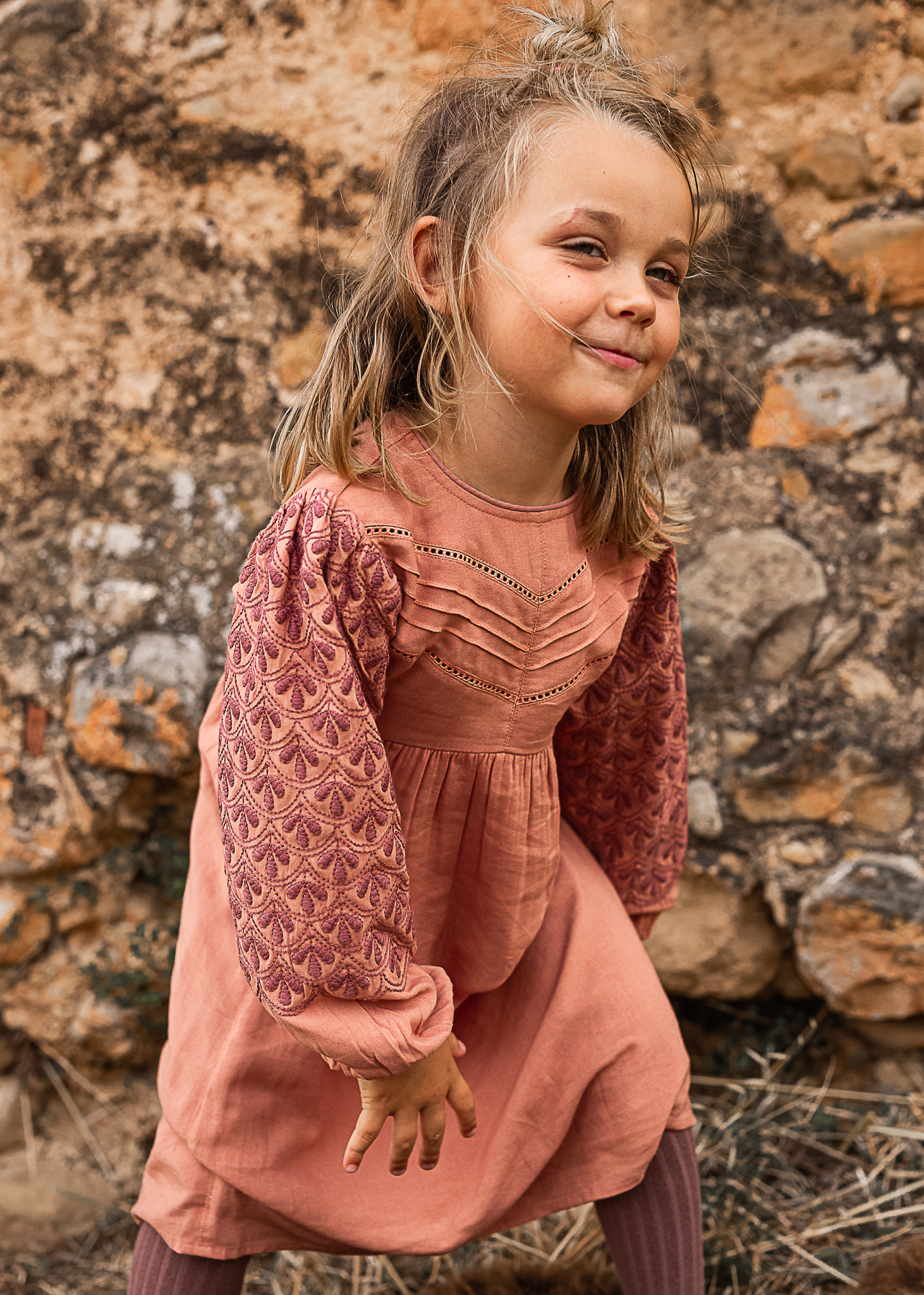 niña delante de un muro de piedra de una Masia en Pla de l'Estany en cataluña, españa.