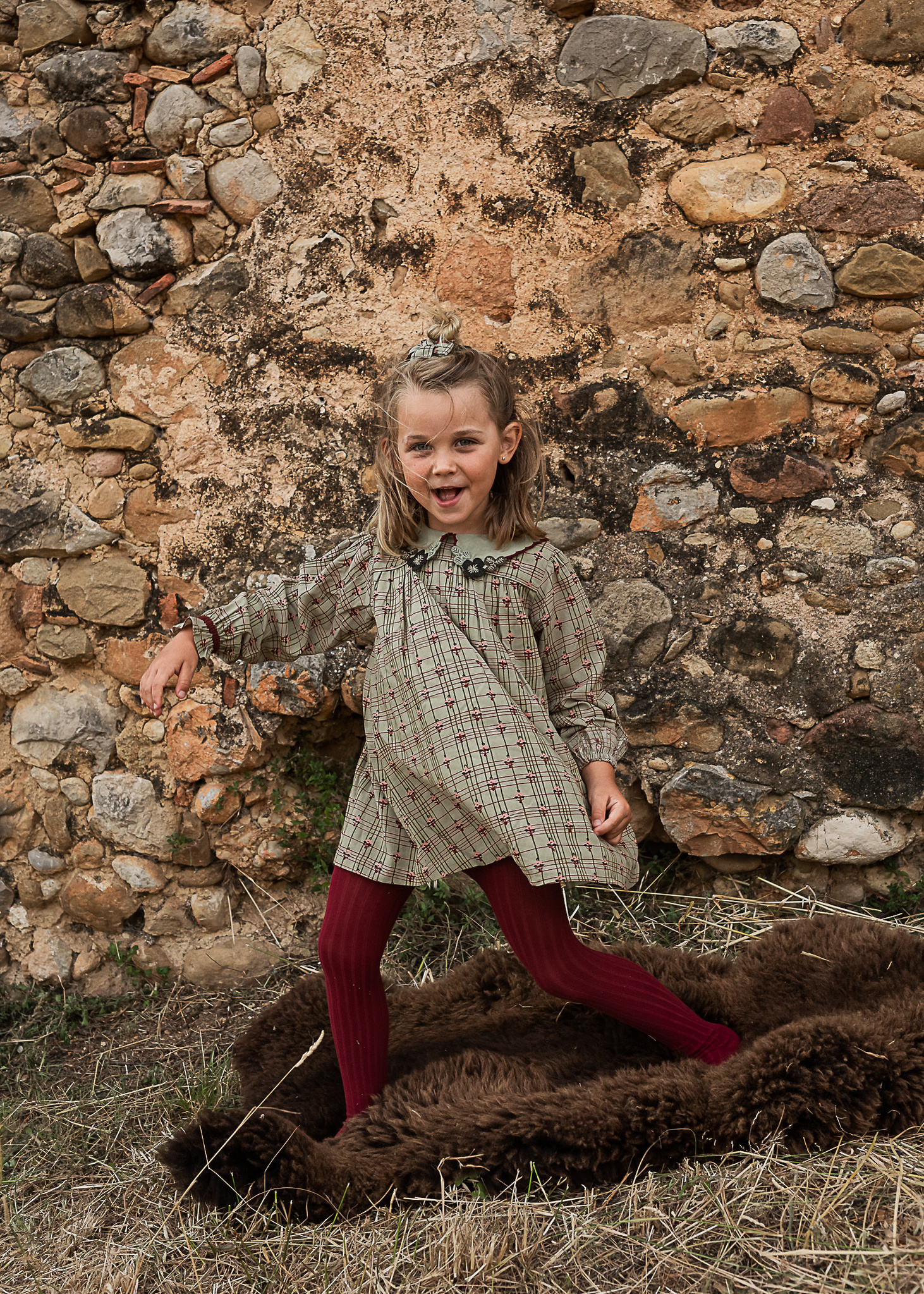 niña jugando delante de un muro de piedra de una Masia en Pla de l'Estany en cataluña, españa.