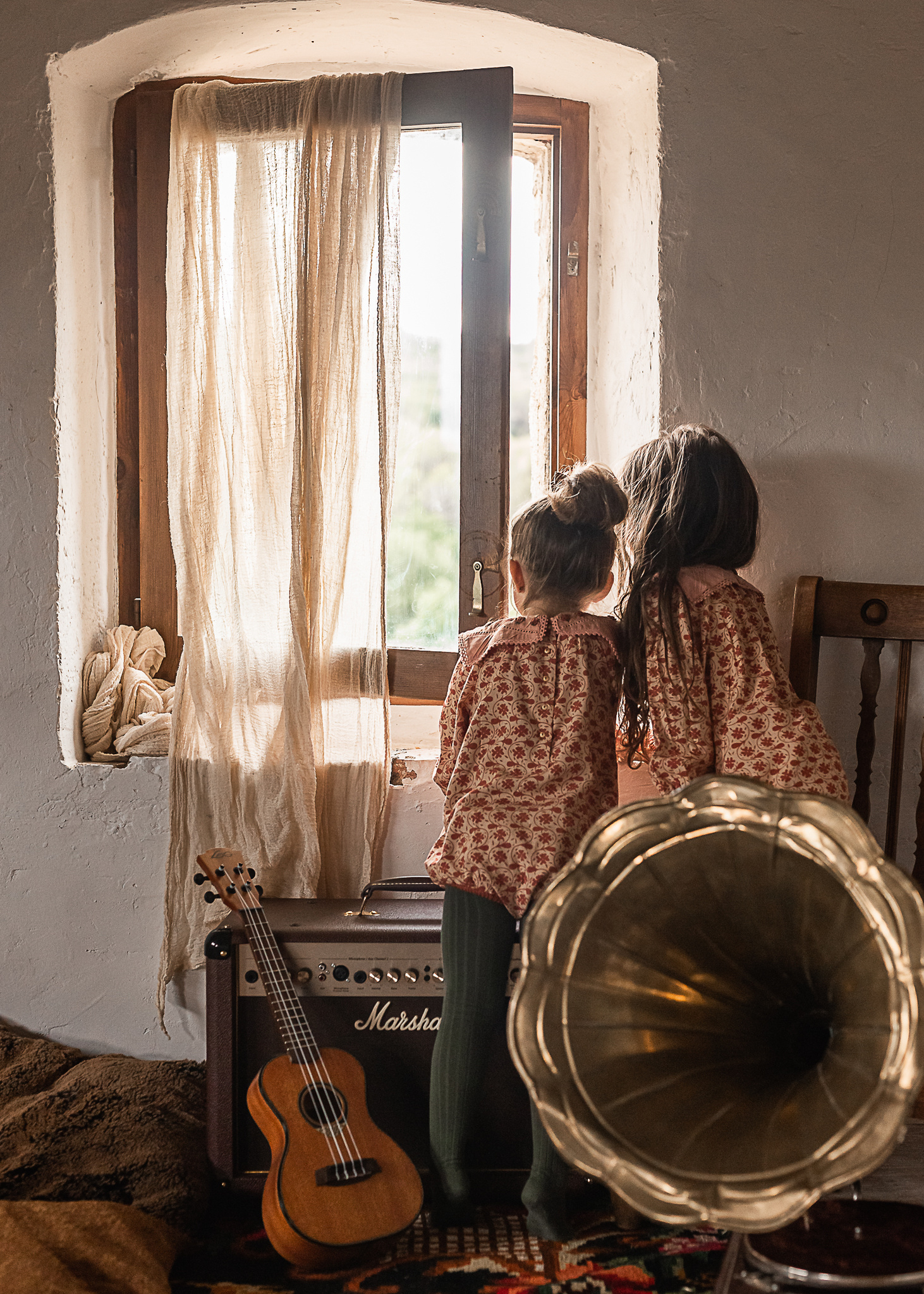 dos niñas mirando por la ventana, con instrumentos en una Masia del Pla de l'Estany, girona, spain