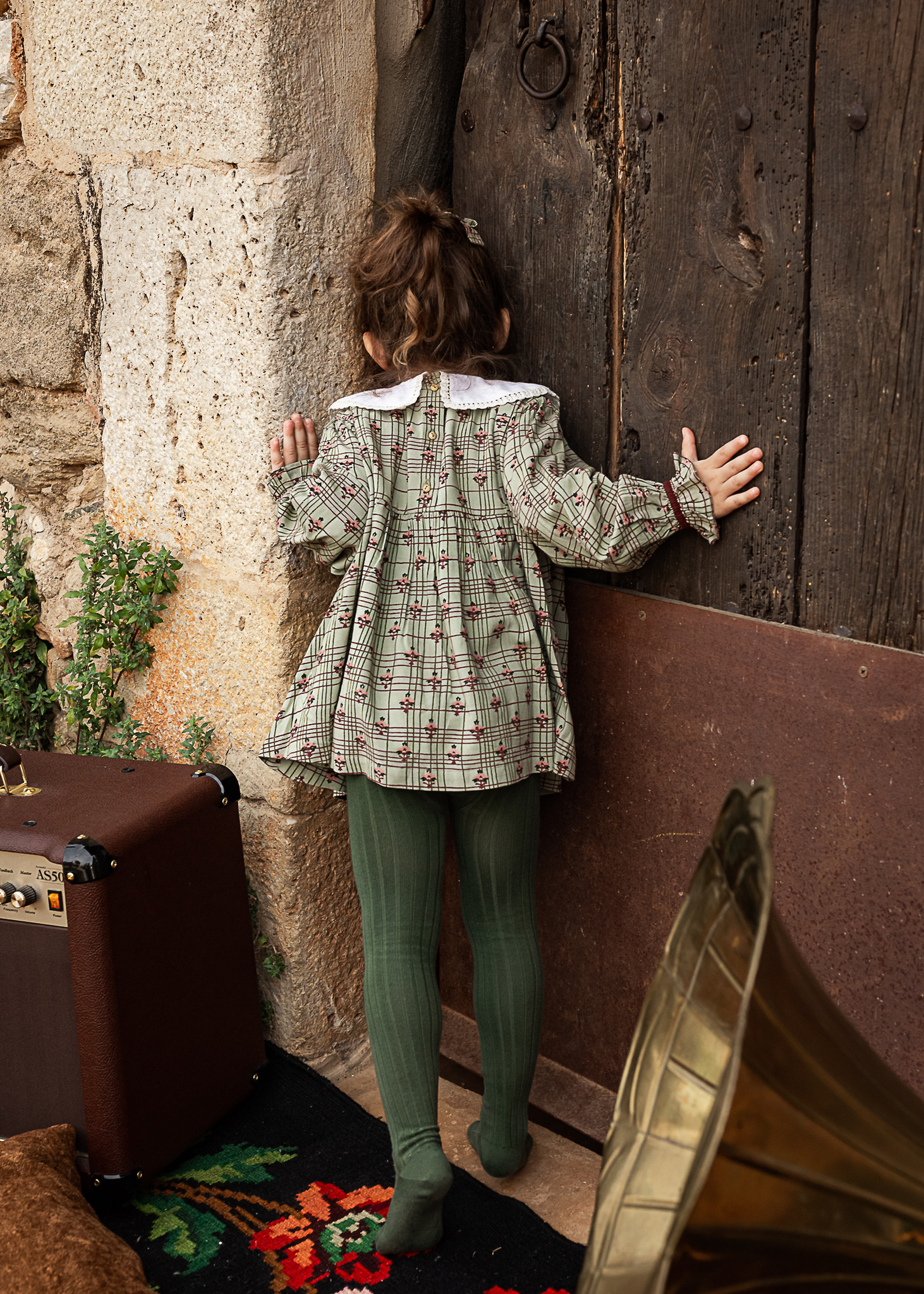 niña mirando por la puerta de una Masia en Pla de l'Estany en cataluña, españa.