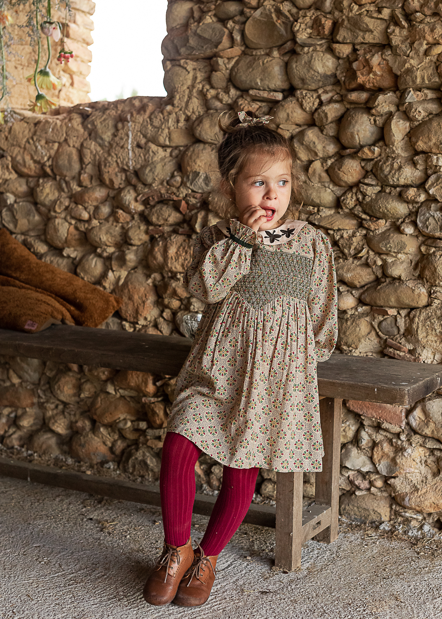 niña apoyada en un banco, comiendo pasas, en un pajar de una Masia en Pla de l'Estany, girona, españa
