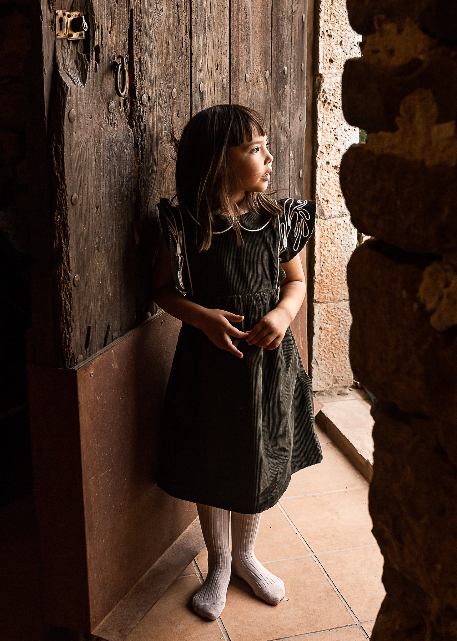 niña saliendo por la puerta de una Masia en Pla de l'Estany en cataluña, españa.