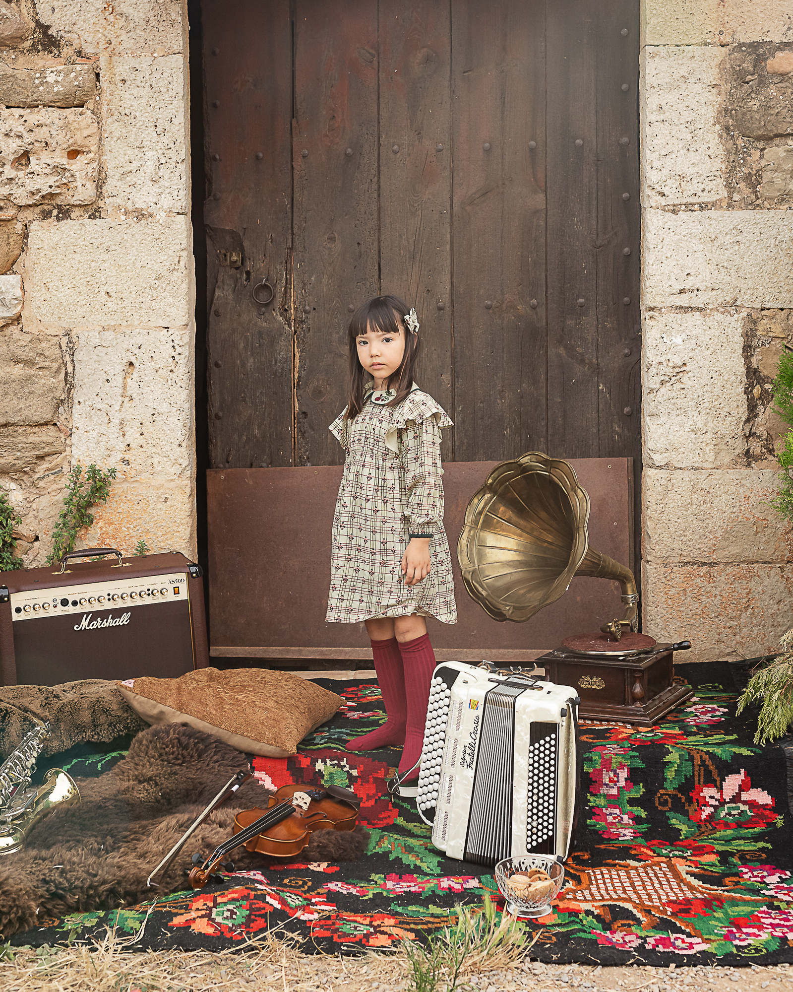  niña y un acordeón frente de la puerta de una Masia en Pla de l'Estany en cataluña, españa.