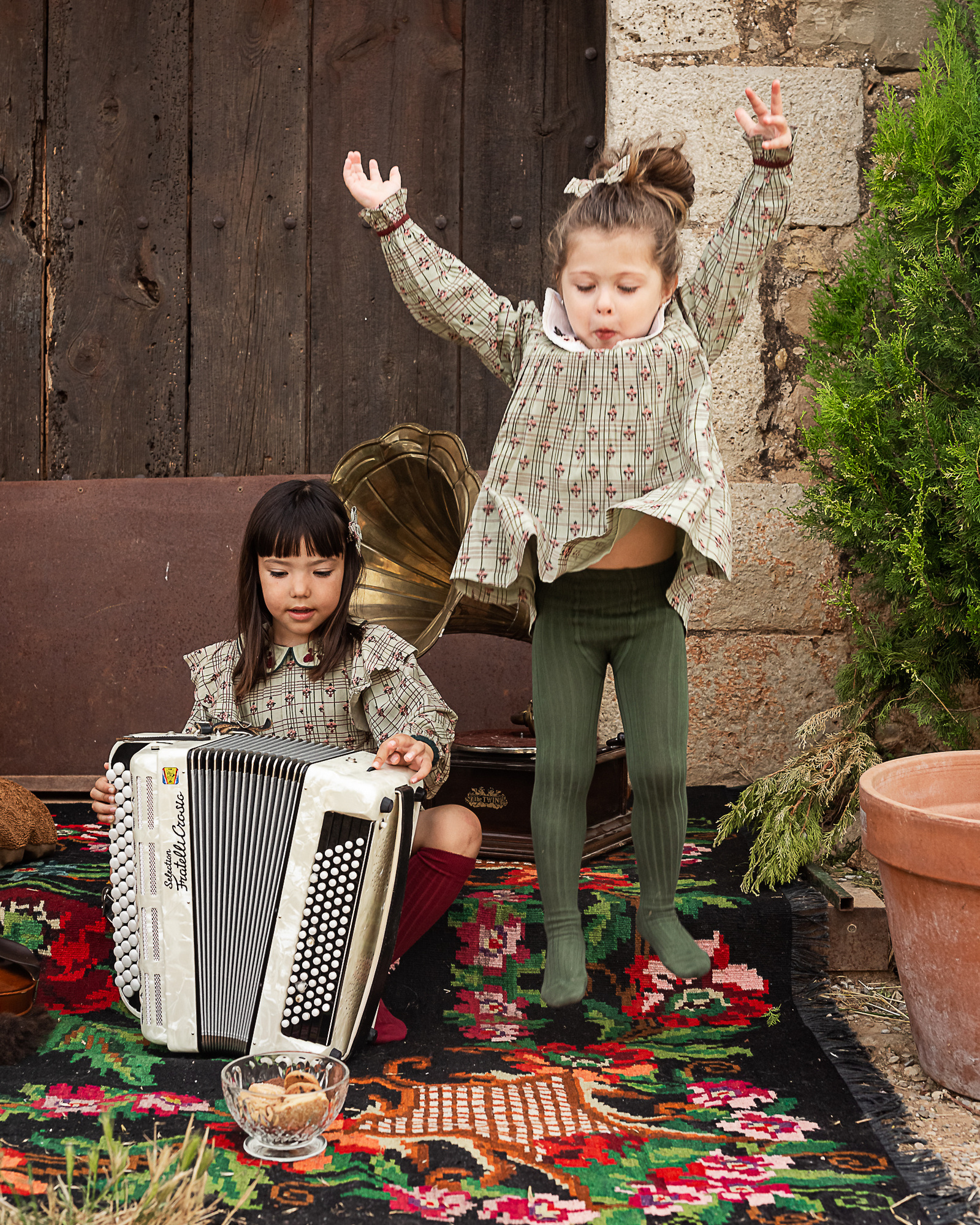 dos niñas y un acordeón frente de la puerta de una Masia en Pla de l'Estany en cataluña, españa.