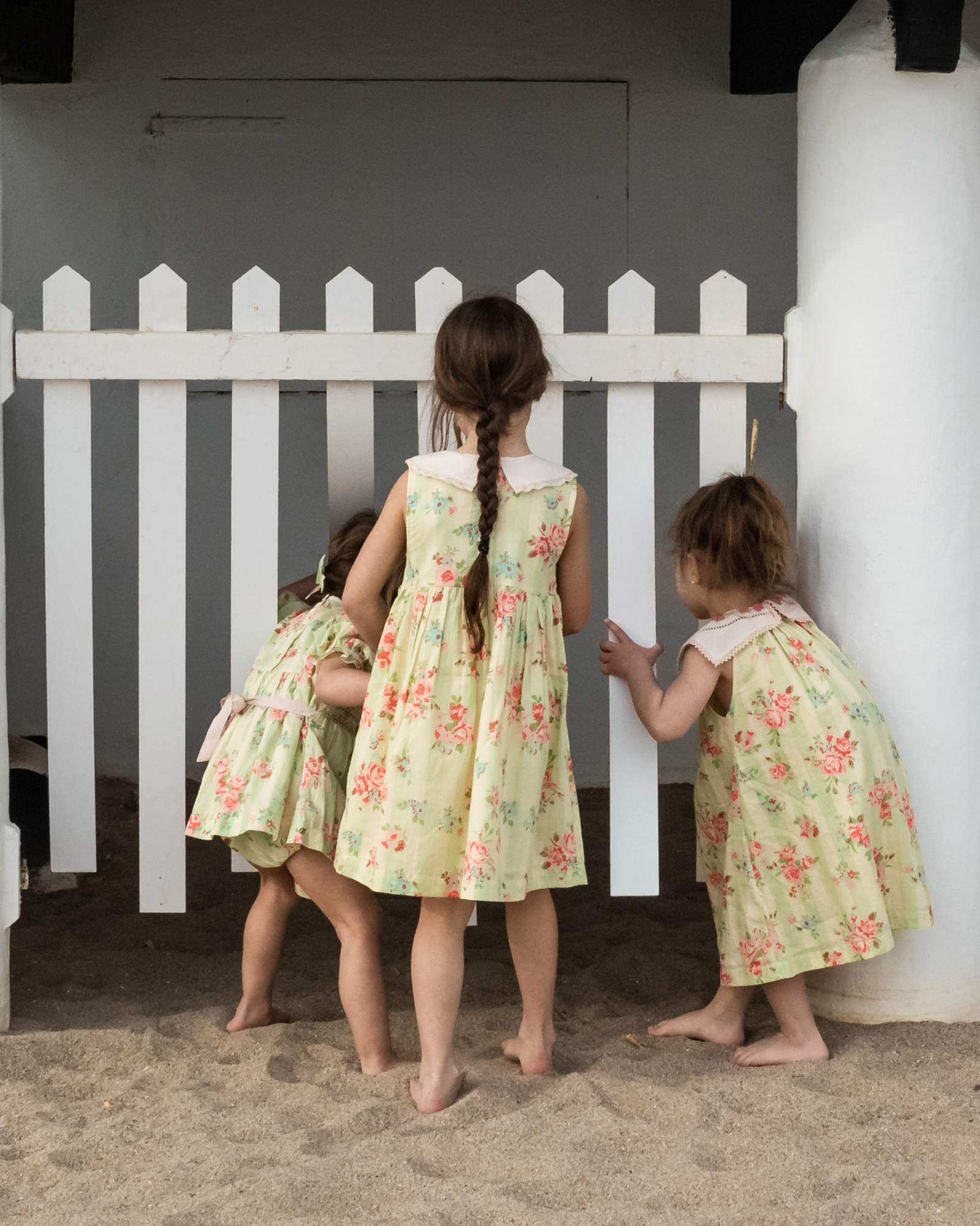 tres niñas de la mano curioseando en la playa las casetas del Garraf en barcelona, españa