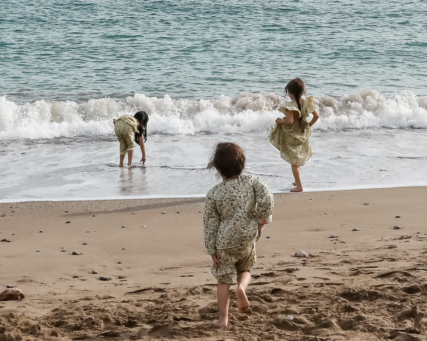 cuatro niñas jugando con las olas en la playa las casetas del Garraf en barcelona, españa
