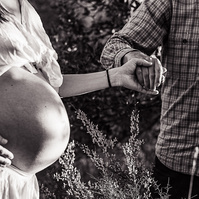 mujer embarazada es llevada de la mano por su marido en los campos del playita de l'estany