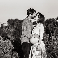 fotografía de una pareja besándoselas  ella está embarazada  de 38 semanas, en los campos floridos de Pla de l'Estany, en girona, españa.