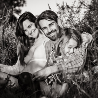retrato de una familia con niña pequeña ella está embarazada  de 38 semanas, en los campos floridos de Pla de l'Estany, en girona, españa.