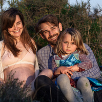 fotografía de una familia de tres ella está embarazada  de 38 semanas, en los campos floridos de Pla de l'Estany, en girona, españa.