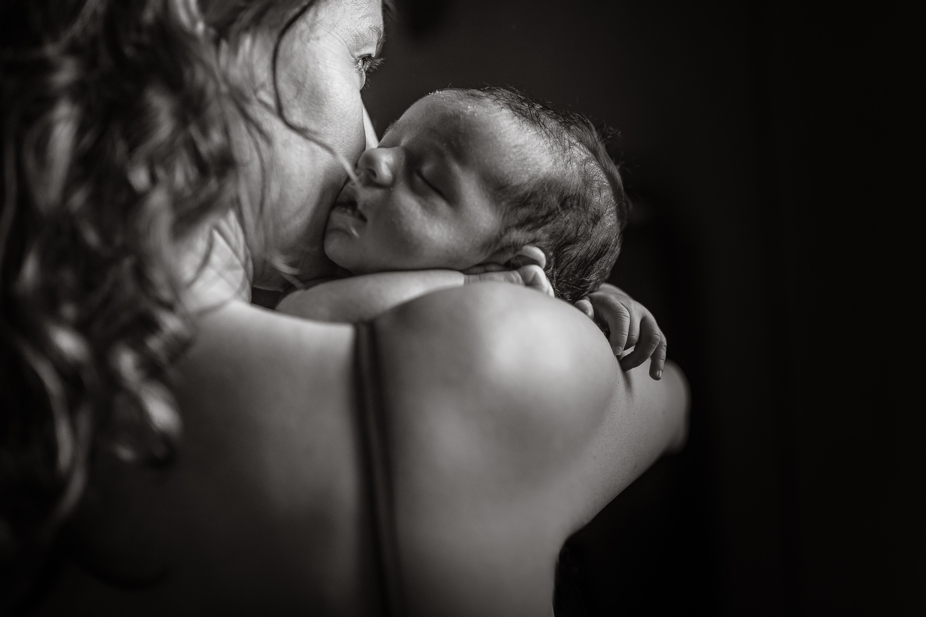 madre abrazando a su recién nacido iluminada por la luz de su ventana. Manuela Franjou barcelona birth photographer