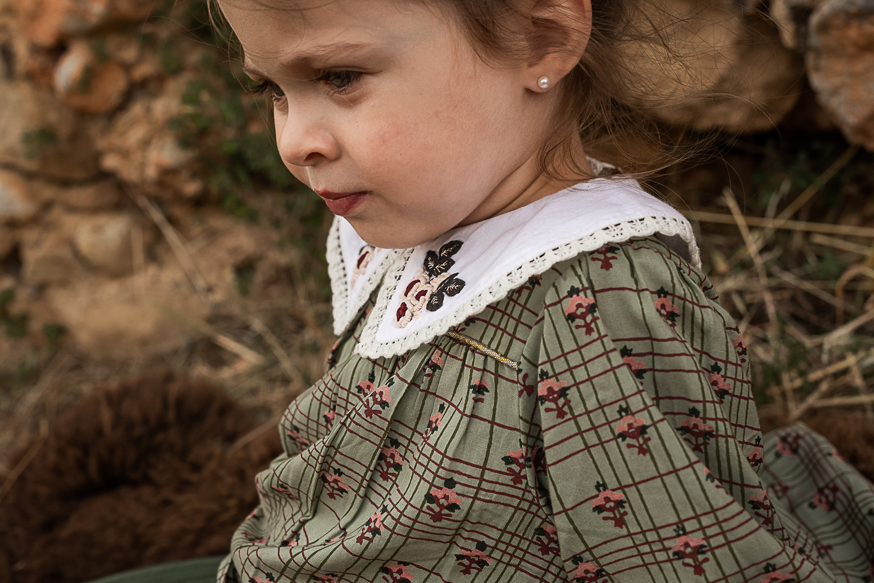 retrato de una niña delante de un muro de piedra de una Masia en Pla de l'Estany en cataluña, españa.