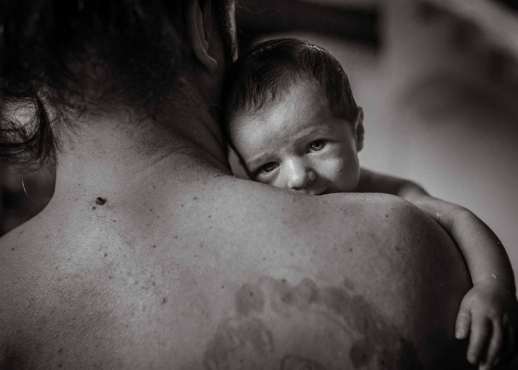 padre abrazando  a su recién nacido iluminada por la luz de su ventana. Manuela Franjou barcelona birth photographer