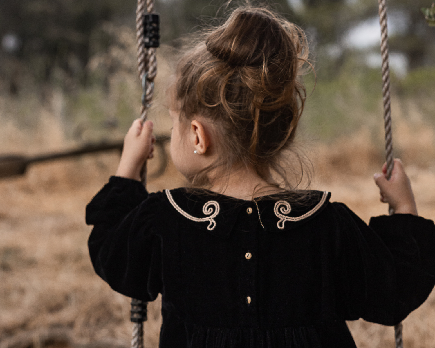 una niña sentada en un columpio en el jardín de una Masia del Pla de l'Estany, girona, españa.