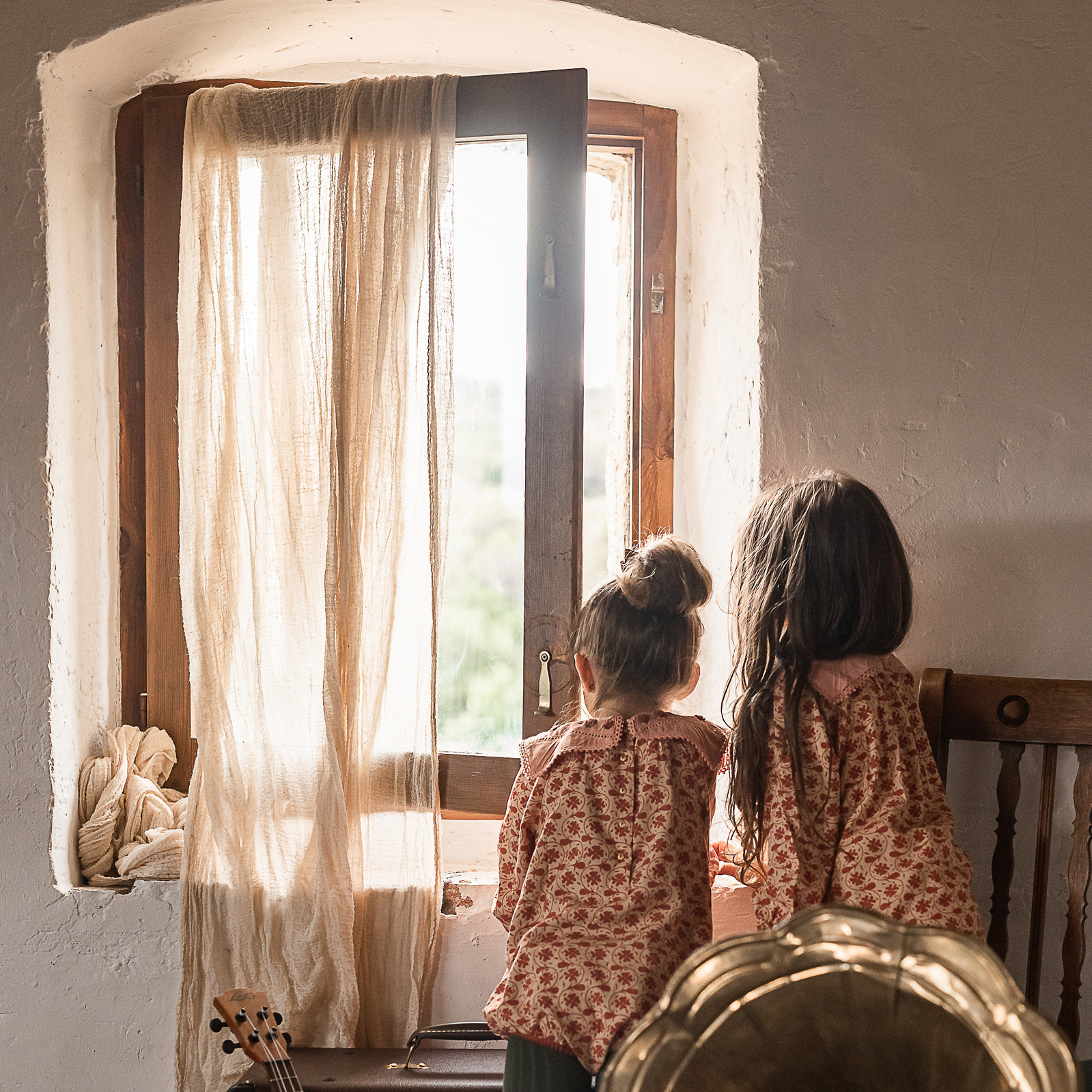dos niñas mirando por la ventana, con instrumentos en una Masia del Pla de l'Estany, girona, spain