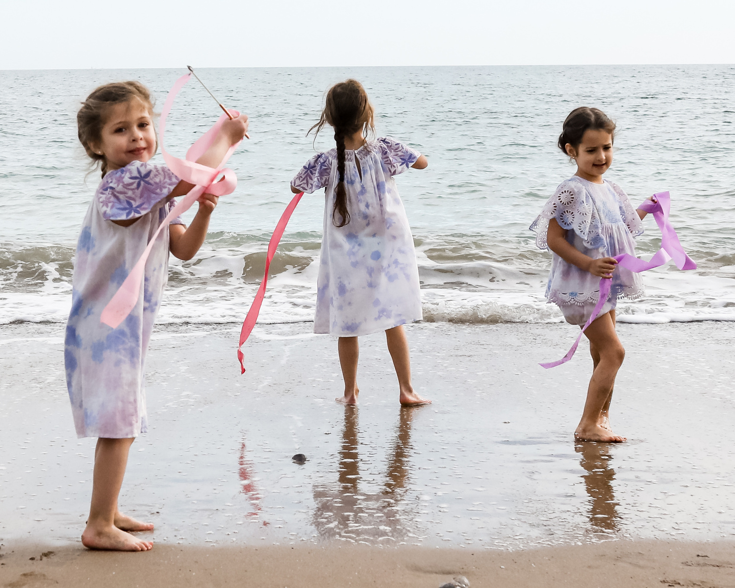 tres niñas jugando con las olas en la playa las casetas del Garraf en barcelona, españa