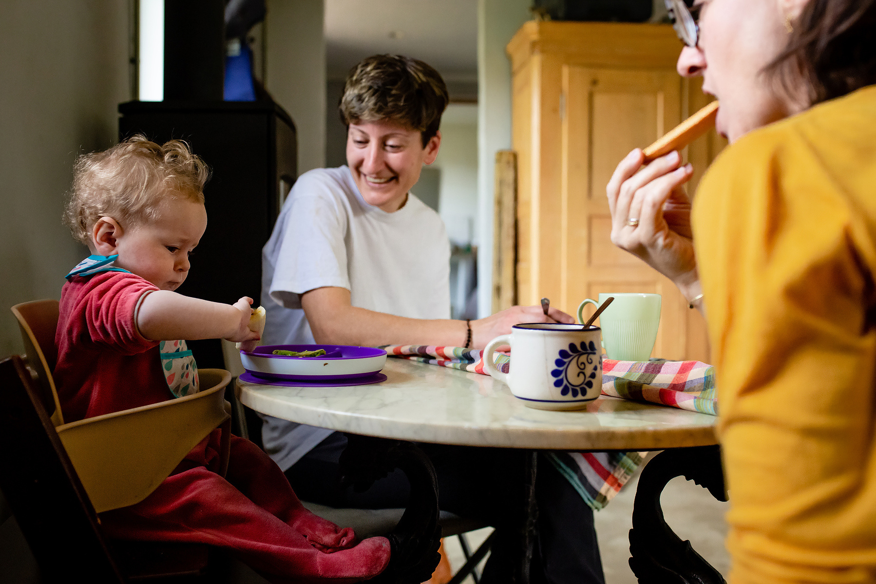 dos mamás compartiendo con su bebé en la mesa de la cocina, Manuela Franjou fotografia de familia