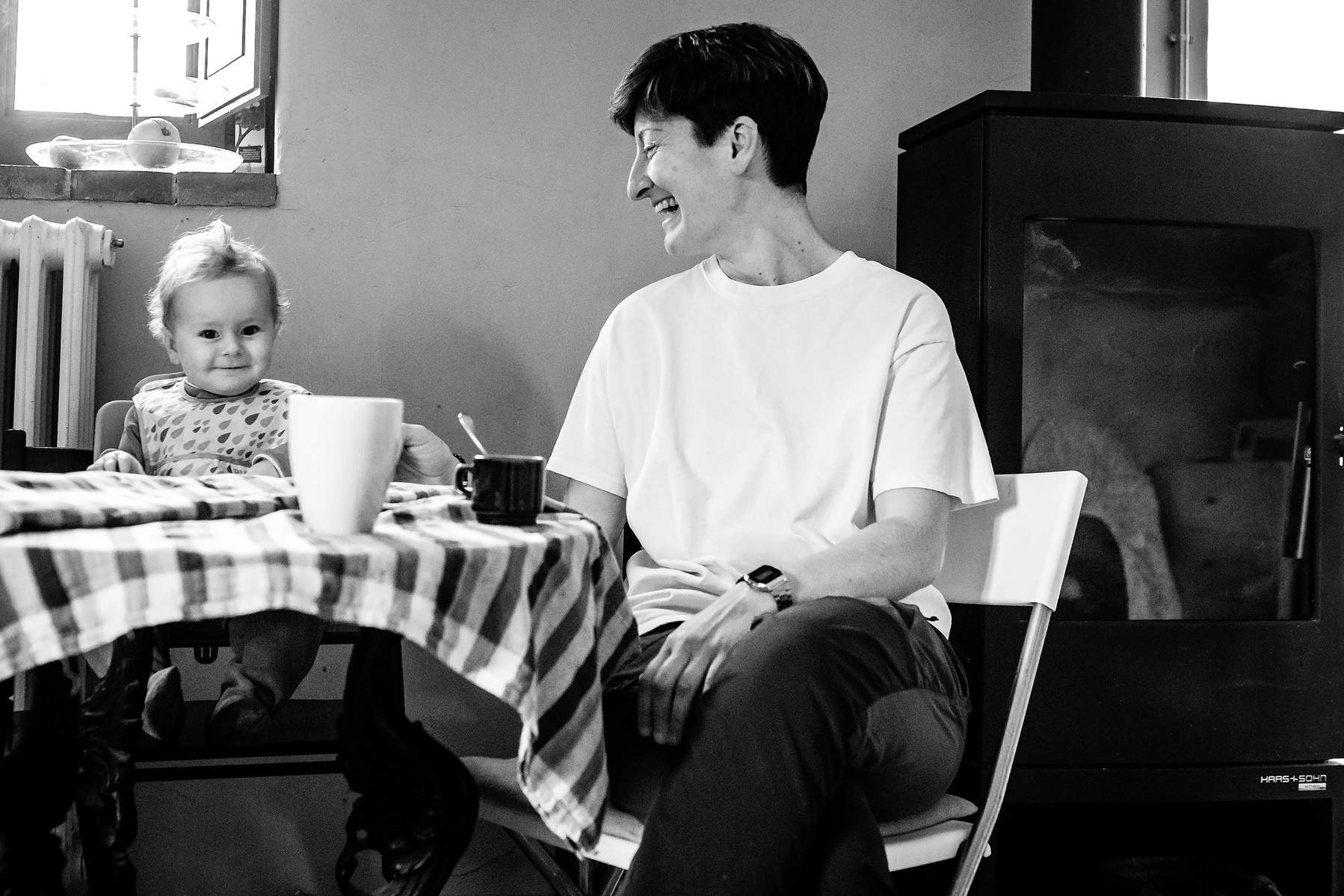 mamá riendo junto a su bebe en la mesa de la cocina, Manuela Franjou fotografia de familia