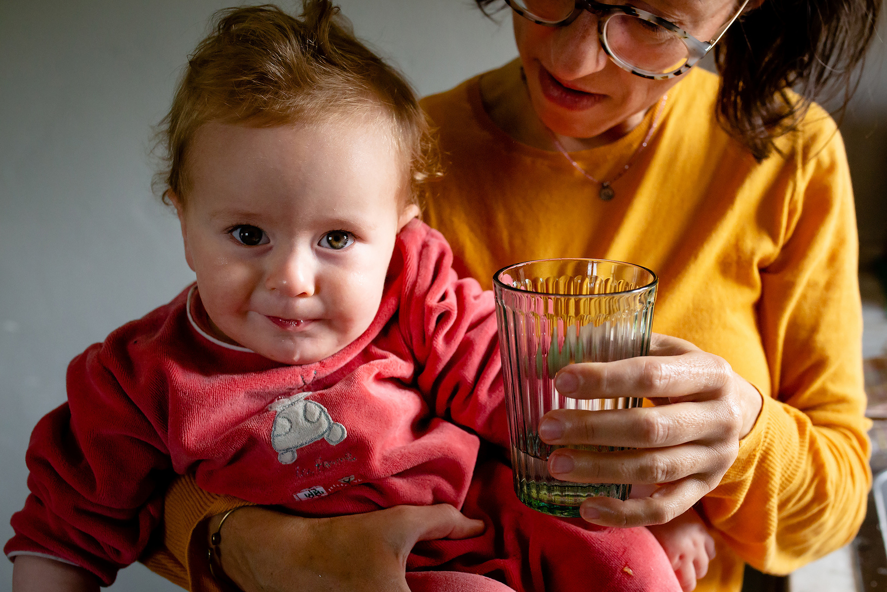 mamá ofreciendo un vaso de agua a su bebe , fotografia de familia Manuela Franjou
