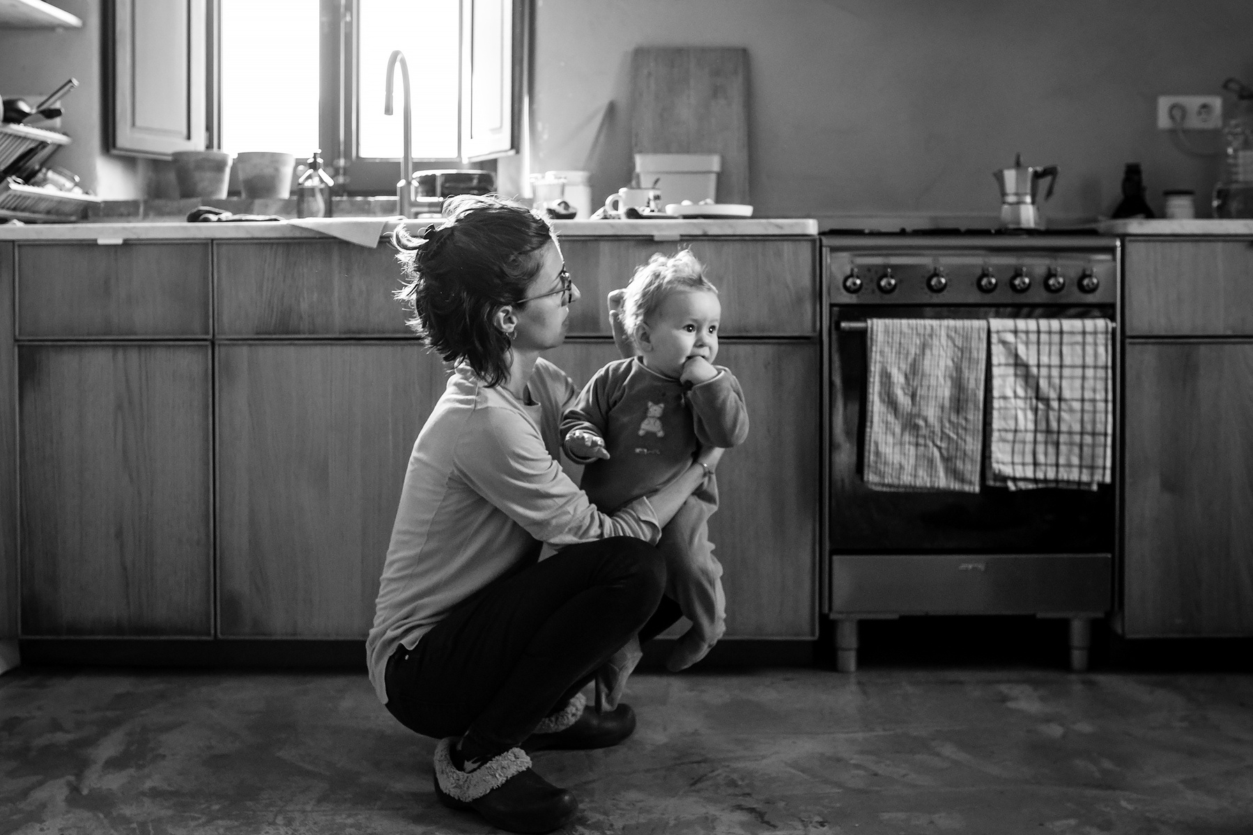 Madre sosteniendo en brazos, en su cocina a su hijo de 11 meses. Fotografía de familia, Manuela Franjou
