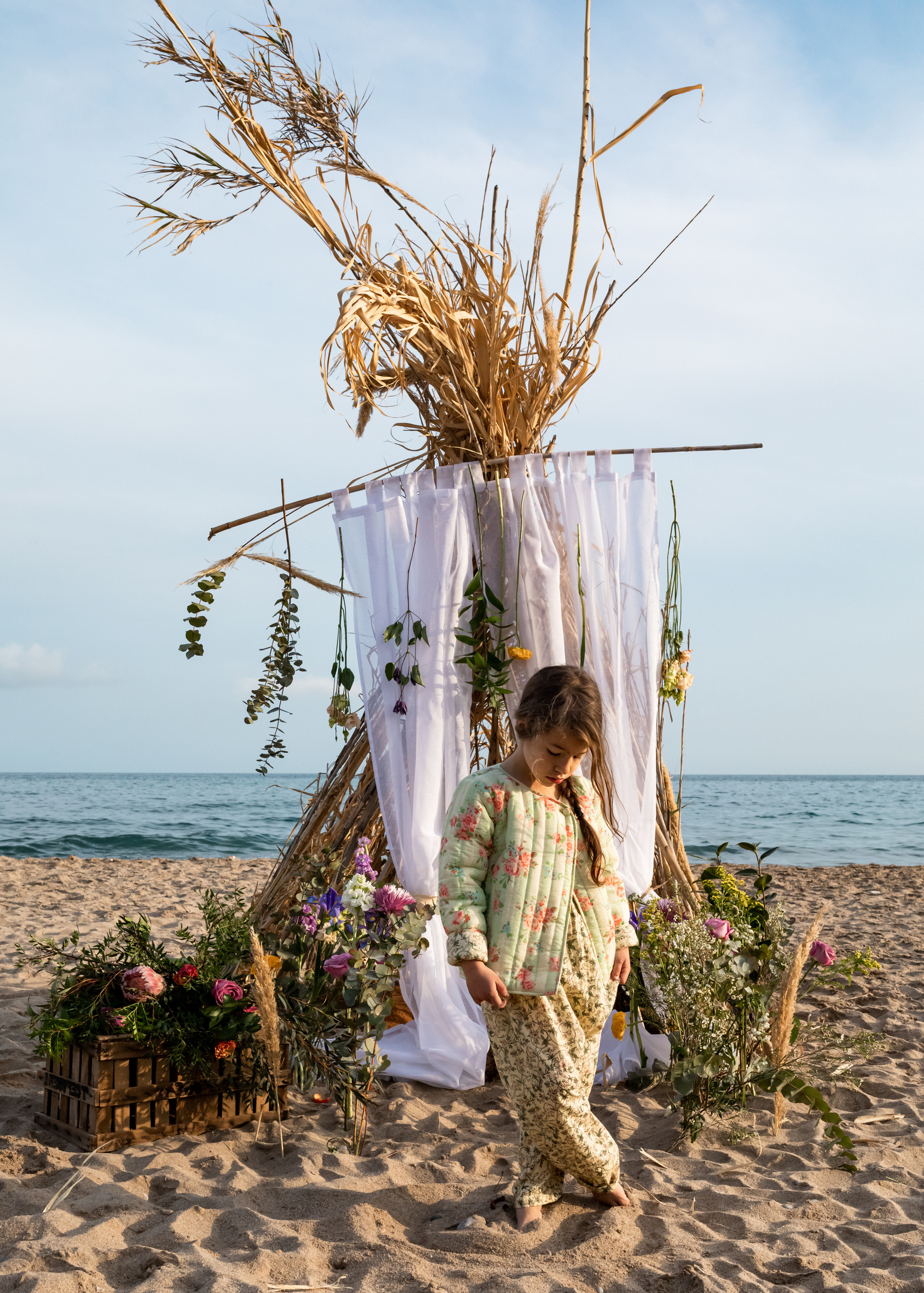 niña delante de una cabaña de ramas  en la playa las casetas del Garraf en barcelona, españa