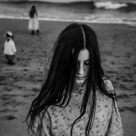 retrato de niña y sus hermanos a lo lejos en la playa del Empordá