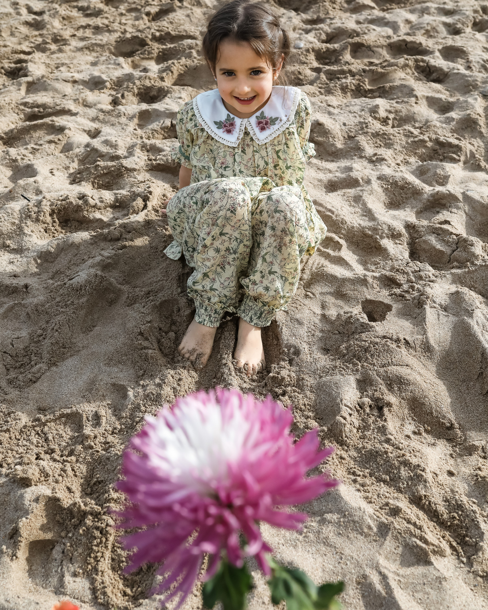 niña en la arena con flor delante en la playa las casetas del Garraf en barcelona, españa
