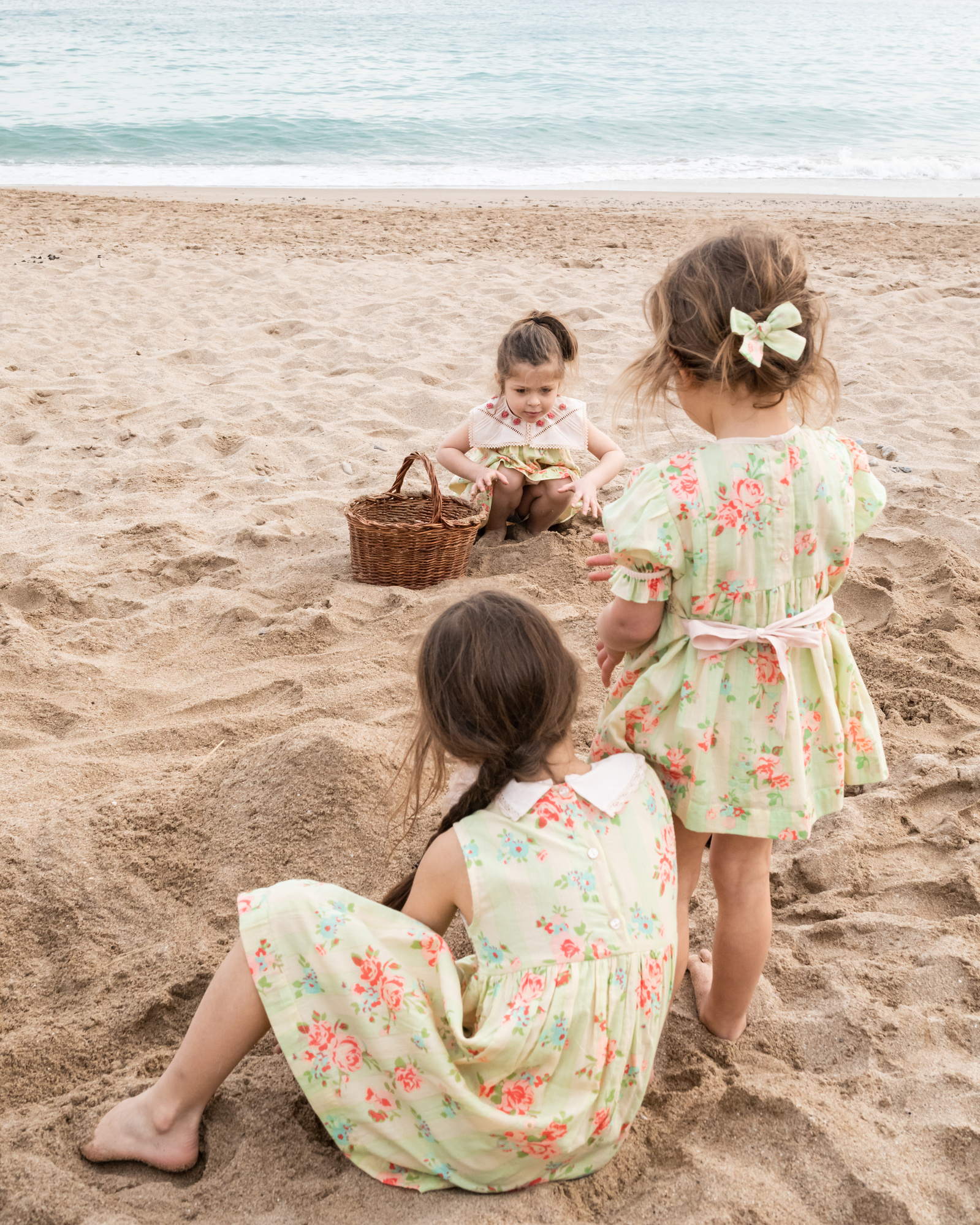 tres niñas jugando en la  la arena de la playa las casetas del Garraf en barcelona, españa