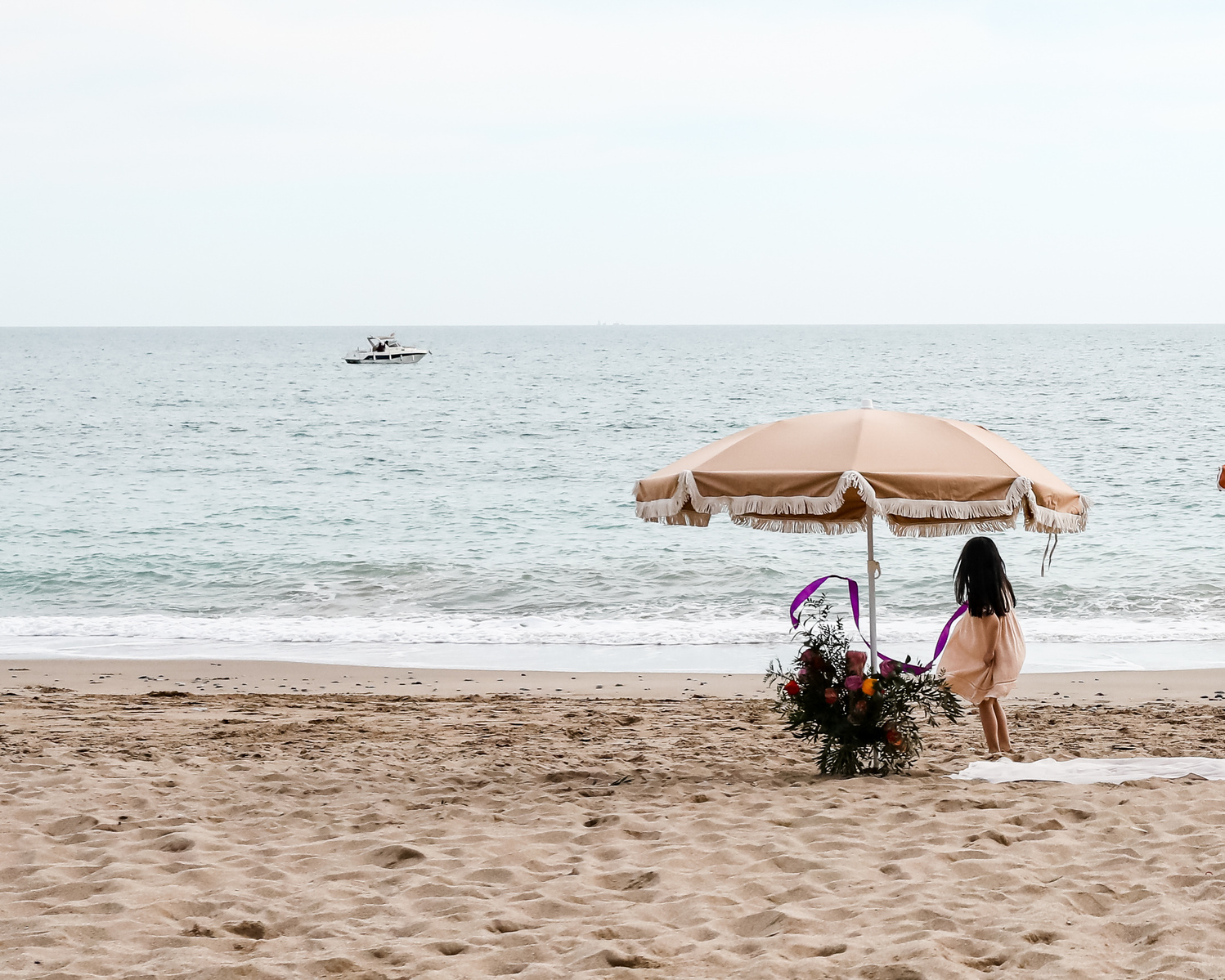 niña cerca de un parasol mira el mar  en la playa las casetas del Garraf en barcelona, españa