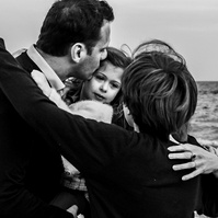 Familia abrazando a la hija y hermana pequeña en la playa de les casetas del Garraf en Cataluña, españa