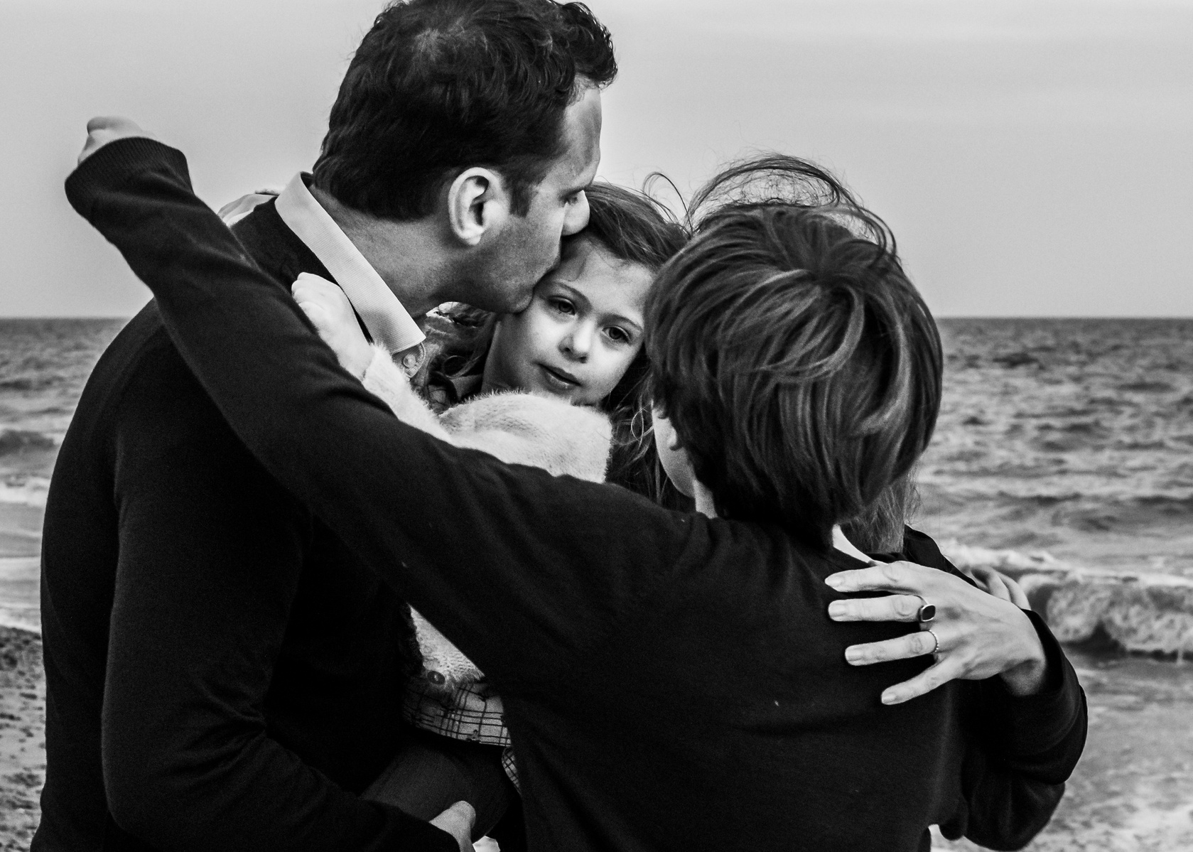 Familia abrazando a la hija y hermana pequeña en la playa de les casetas del Garraf en Cataluña, españa