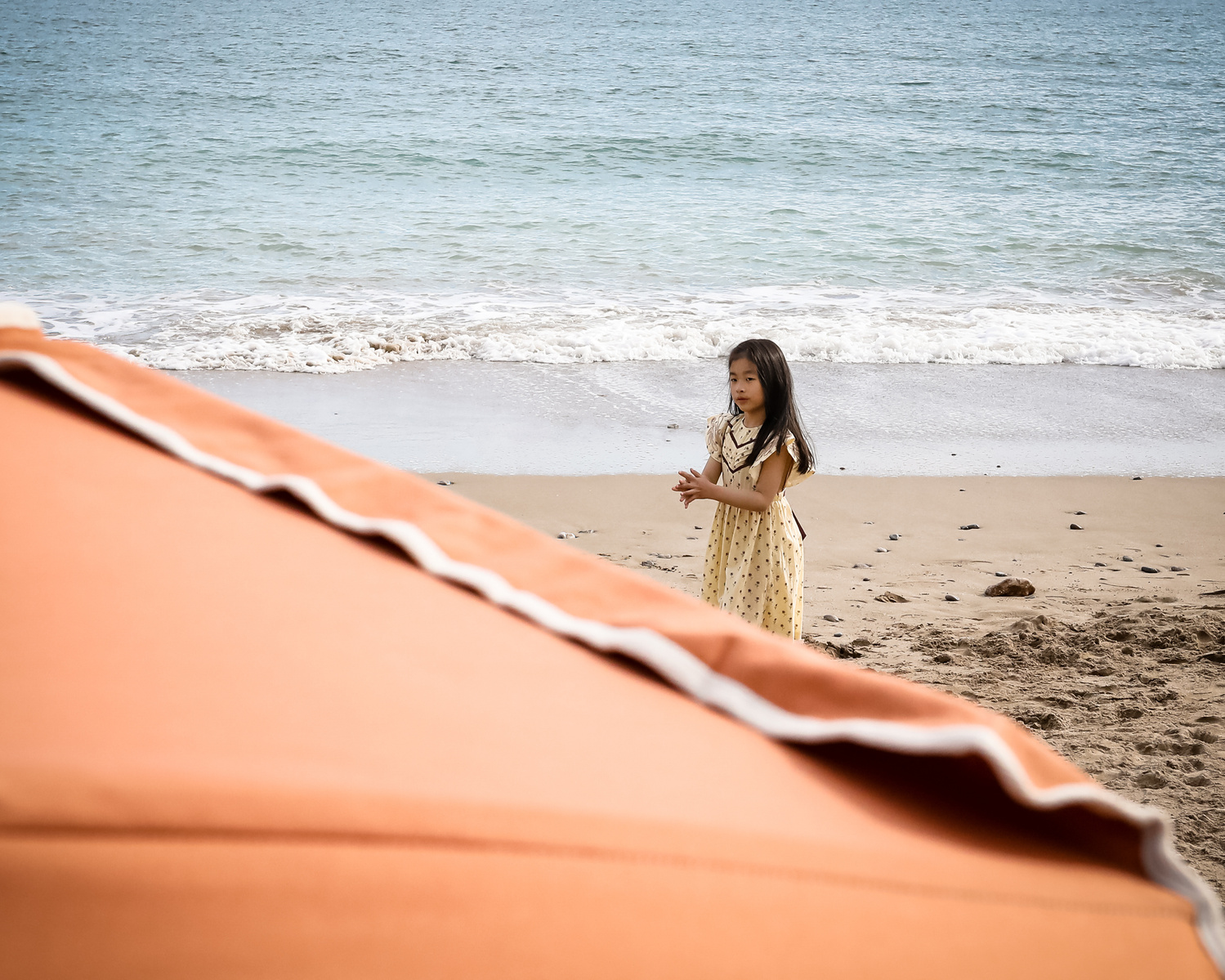 se ve una niña enmarcada por una sombrilla de playa niña en les casetas del Garraf en Barcelona, españa