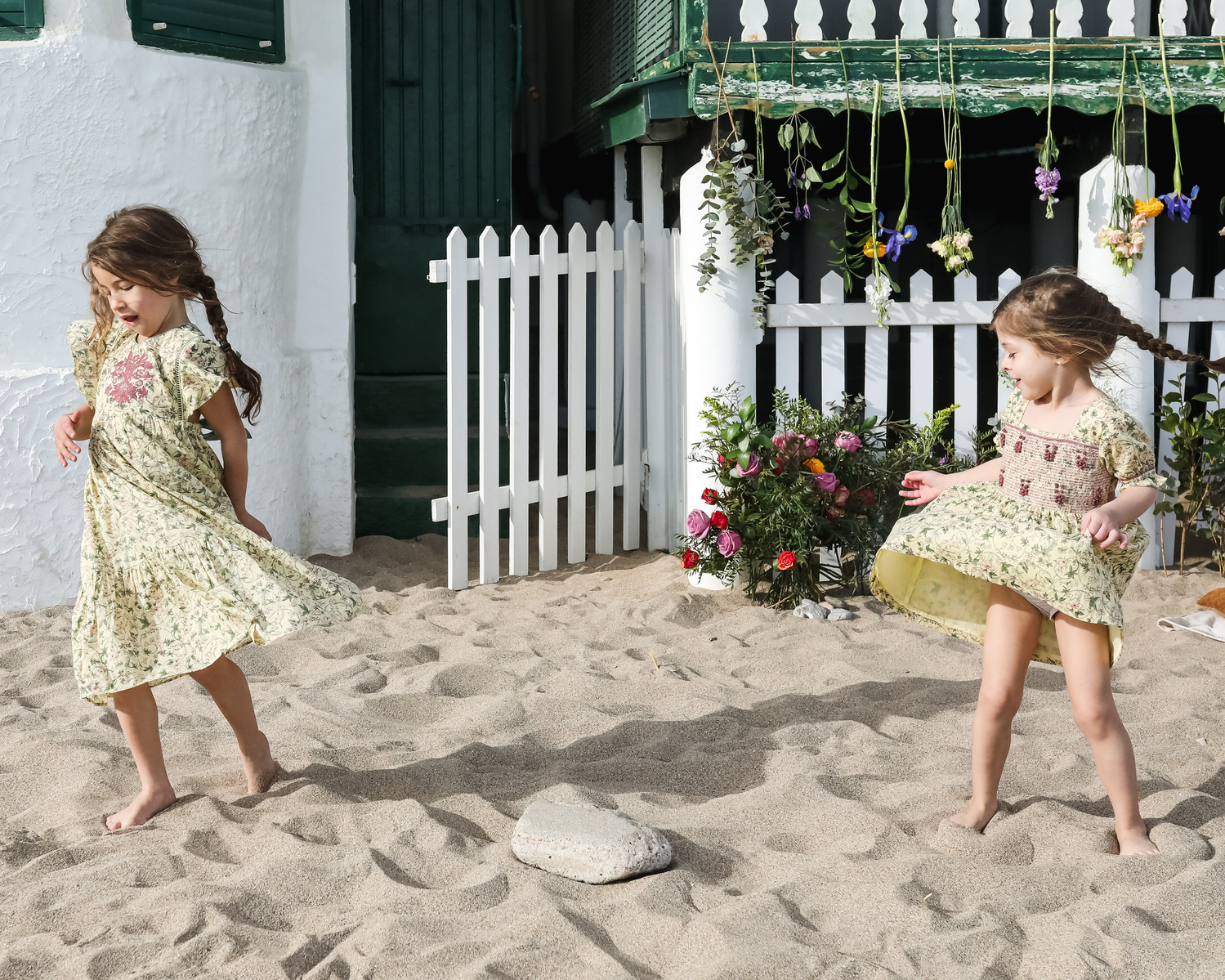 dos niñas dan vueltas a sus vestidos delante de les casetas del Garraf en Barcelona, españa