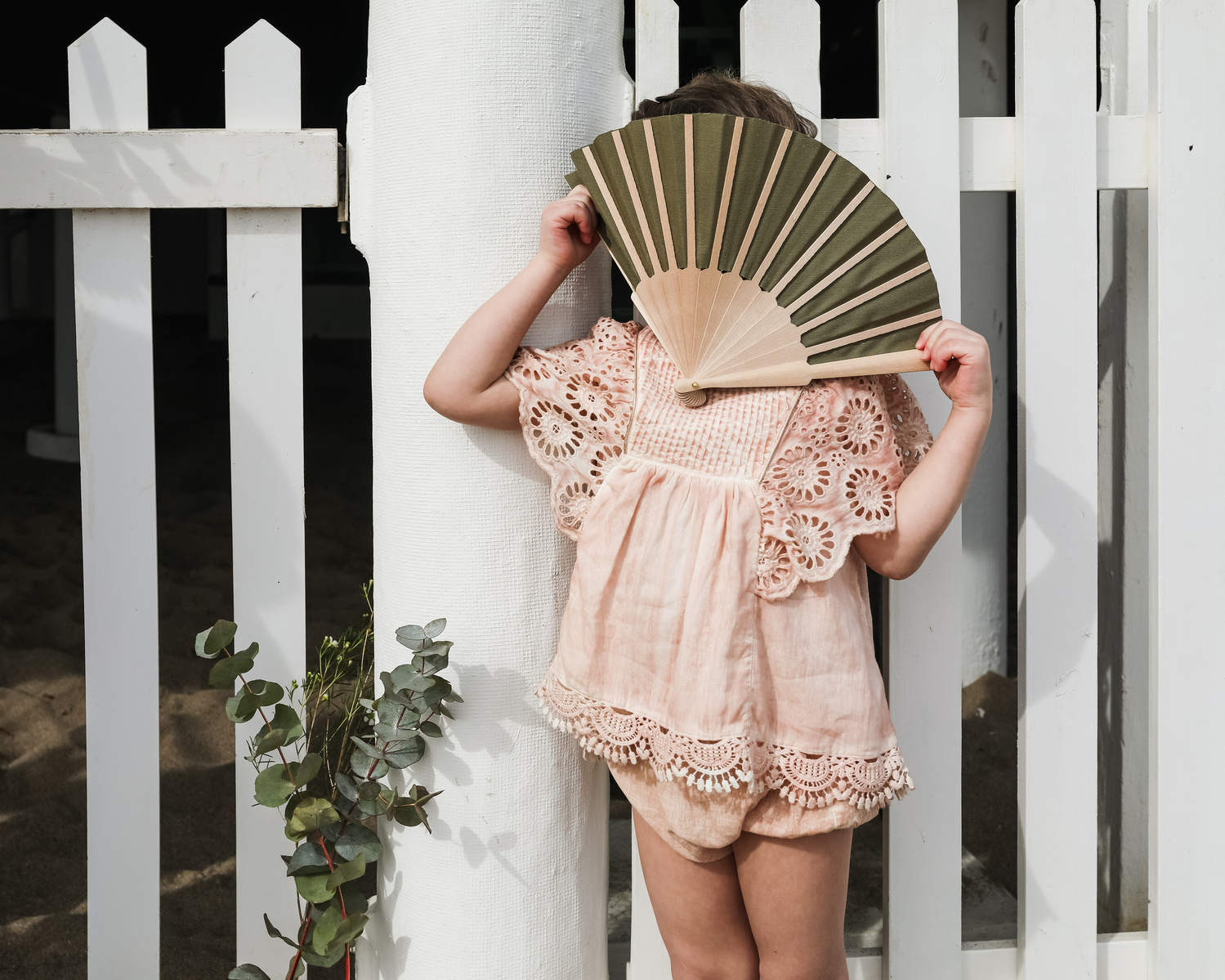 niña se esconde la cara con un abanico delante de les casetas del Garraf en Barcelona, españa