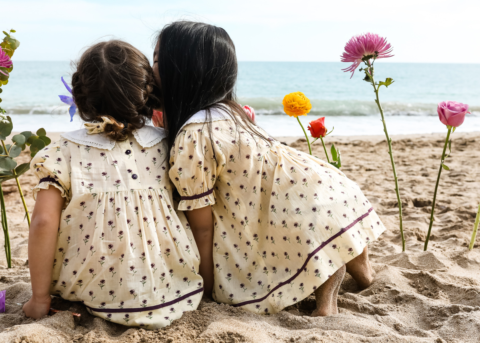niña hablando al oído de su amiga en la playa de les casetas del Garraf en Barcelona, españa