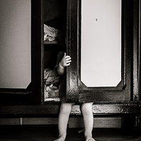 niño pequeño escondiéndose en un armario, sobresalen sus piernas y mano. en cataluña, españa