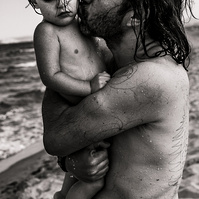 Papa abrazando a su hijo bebe, en una playa del alt empordá en cataluña, españa