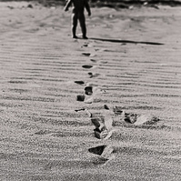 marcas de pies en la arena de un niño pequeño, se ve su silueta en el fondo. alt Empordá, girona, Spain